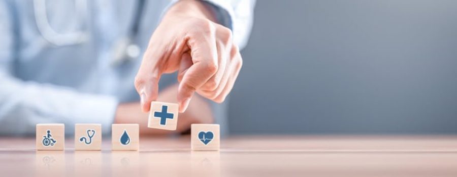 hand picking up a small wooden block with healthcare icon on it