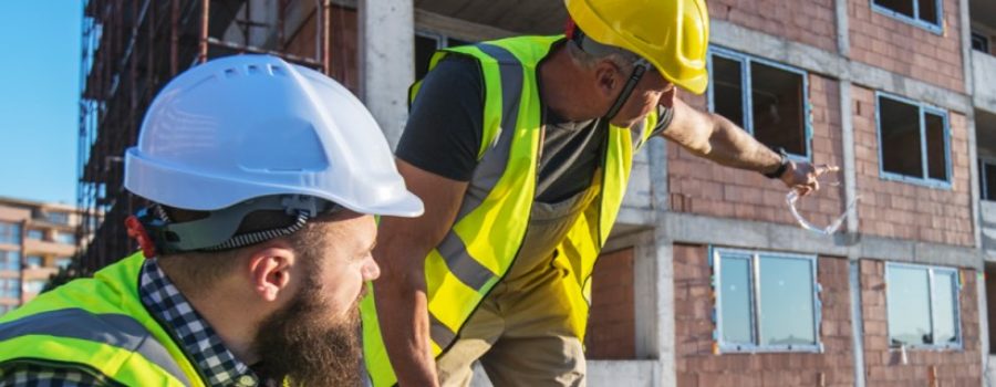 2 construction men looking at building